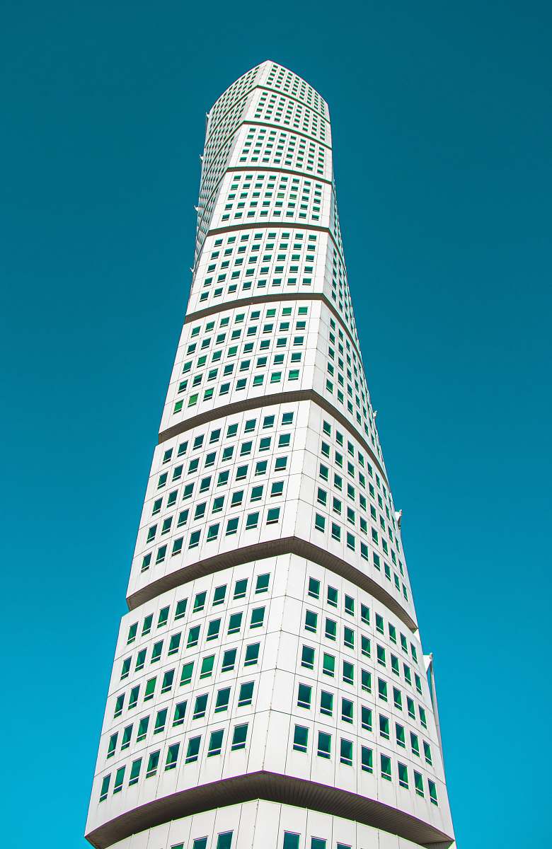 high rise white twisted building under blue sky town